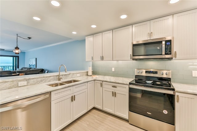 kitchen featuring light wood-type flooring, tasteful backsplash, appliances with stainless steel finishes, and sink