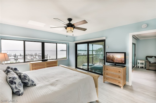 bedroom with access to outside, light hardwood / wood-style floors, ceiling fan, and a water view