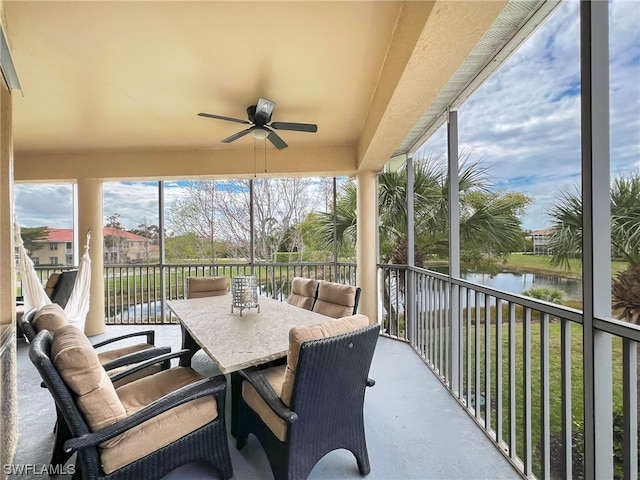 sunroom with a water view and ceiling fan