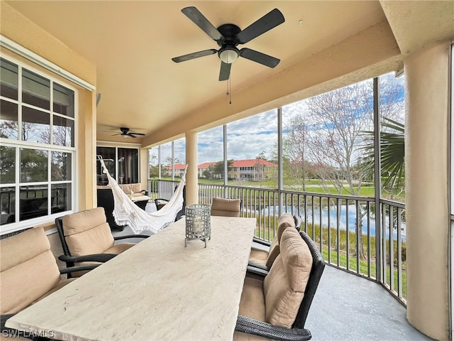 sunroom / solarium with plenty of natural light, ceiling fan, and a water view