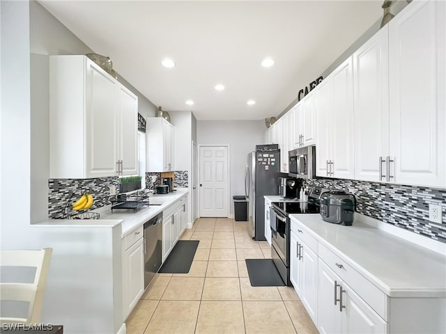 kitchen featuring light tile flooring, backsplash, appliances with stainless steel finishes, and white cabinetry