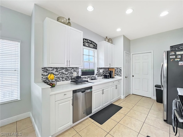 kitchen with light tile floors, appliances with stainless steel finishes, white cabinetry, backsplash, and sink