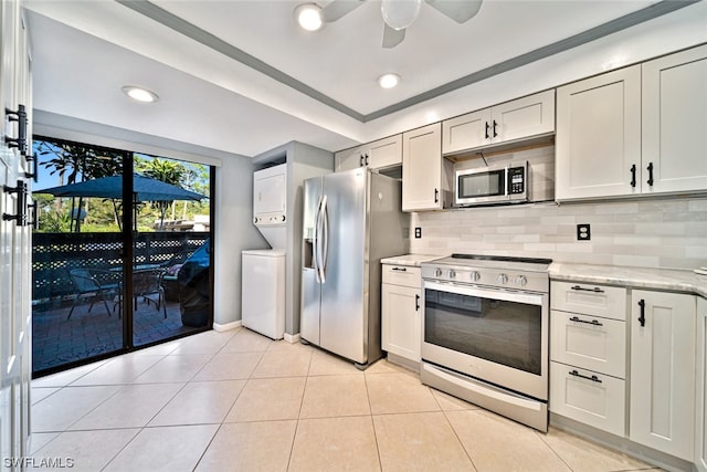 kitchen featuring white cabinets, light stone counters, stainless steel appliances, and stacked washer and clothes dryer