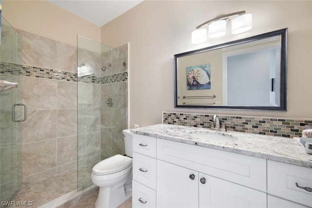 bathroom featuring a shower with door, tasteful backsplash, vanity, and toilet