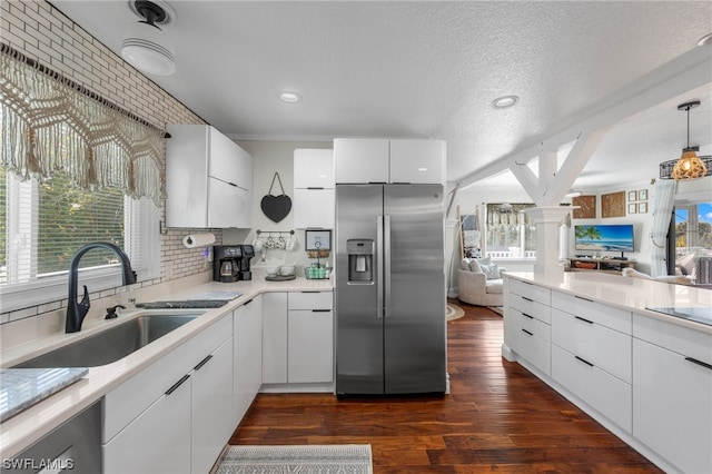 kitchen featuring white cabinets, stainless steel fridge, and a wealth of natural light