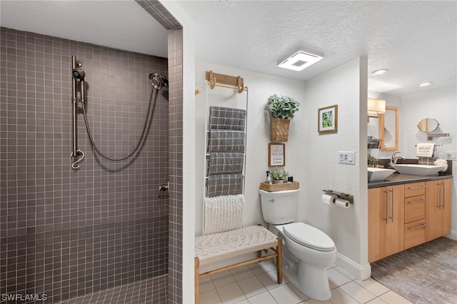 bathroom with tile patterned floors, a tile shower, a textured ceiling, vanity, and toilet