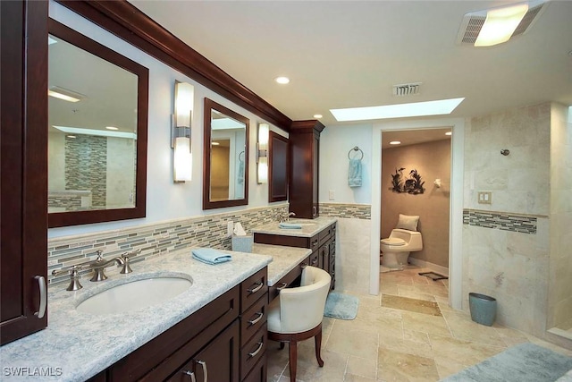 bathroom with vanity, crown molding, a skylight, toilet, and tasteful backsplash