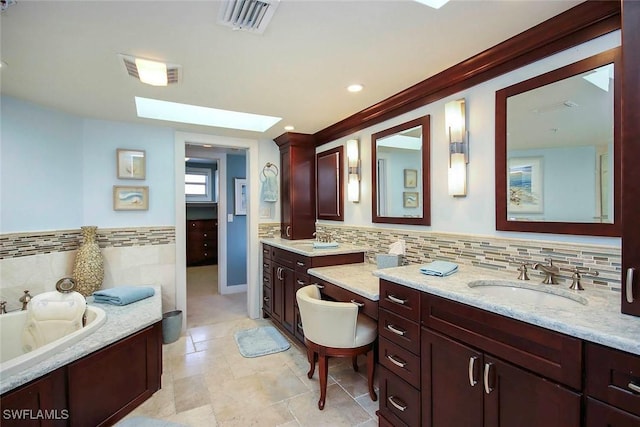 bathroom featuring a bathing tub, vanity, decorative backsplash, and a skylight