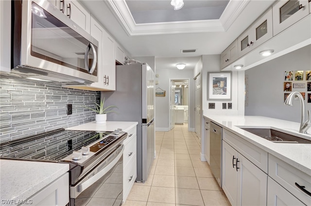 kitchen featuring stainless steel appliances, tasteful backsplash, white cabinetry, a raised ceiling, and sink