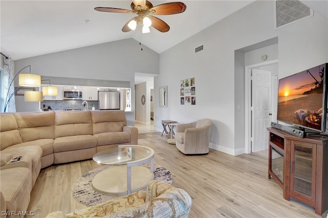 living room with light hardwood / wood-style floors, ceiling fan, high vaulted ceiling, and sink