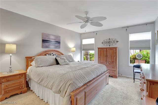 bedroom with multiple windows, ceiling fan, and light colored carpet