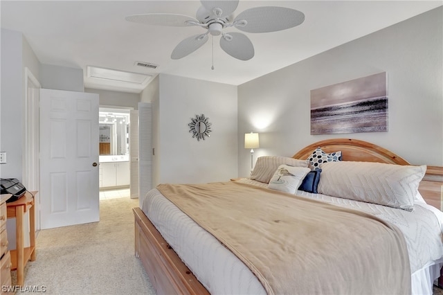 bedroom featuring ceiling fan, ensuite bathroom, and light colored carpet