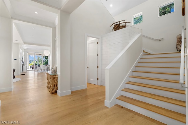 stairs featuring a healthy amount of sunlight, a notable chandelier, and light wood-type flooring