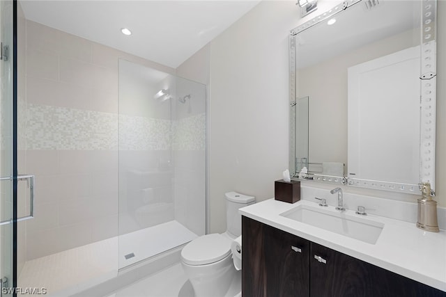 bathroom featuring toilet, a shower with door, and vanity