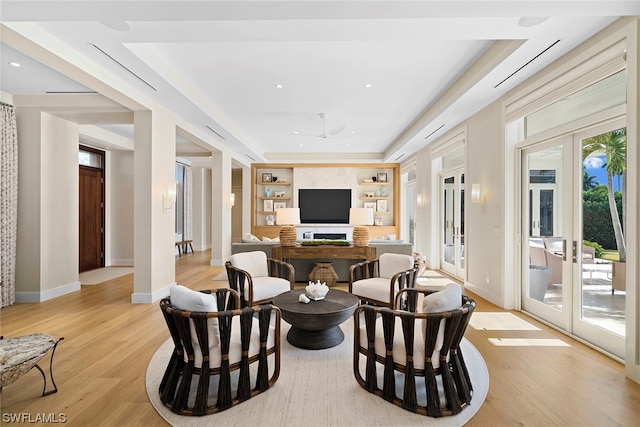 interior space featuring a raised ceiling, french doors, light hardwood / wood-style floors, and built in features