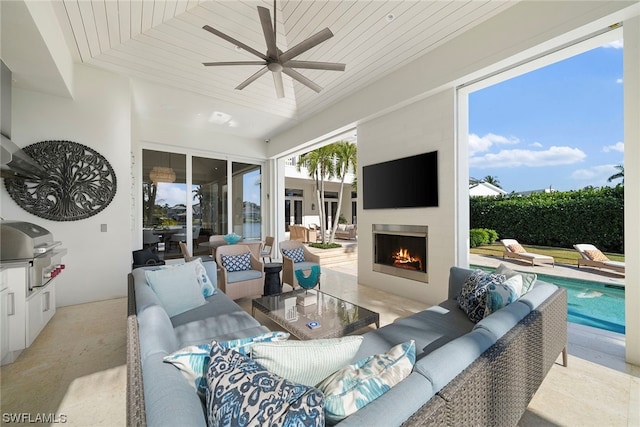 living room with wood ceiling, exterior fireplace, and ceiling fan