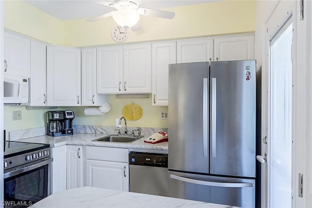 kitchen featuring appliances with stainless steel finishes, light stone counters, white cabinetry, and sink