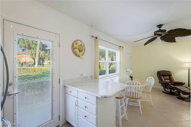 kitchen with kitchen peninsula, white cabinetry, ceiling fan, and light tile patterned flooring