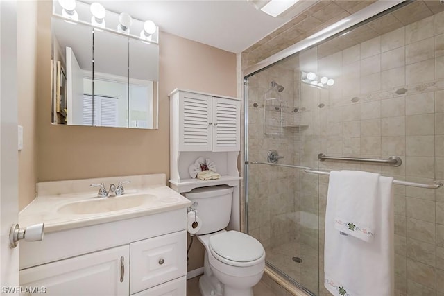 bathroom with vanity, toilet, and a shower with door