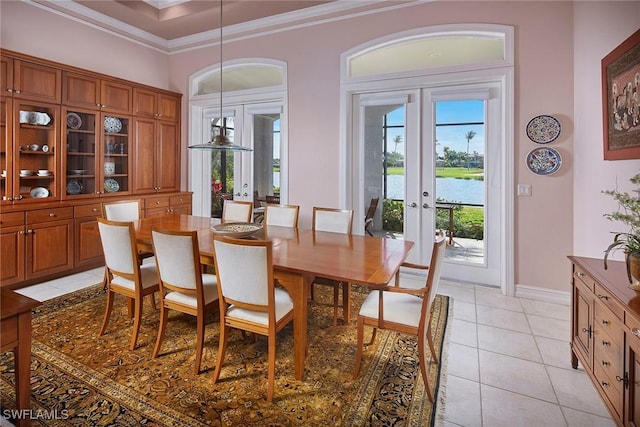 dining space with light tile patterned floors, a water view, baseboards, french doors, and crown molding