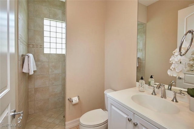 bathroom with tiled shower, vanity, and toilet