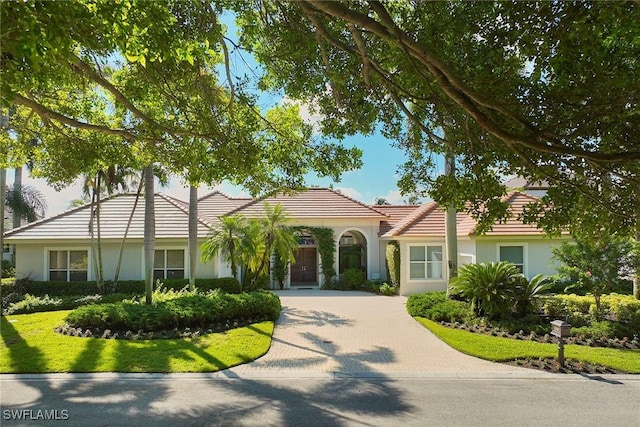 view of front of home with a tiled roof, decorative driveway, and stucco siding