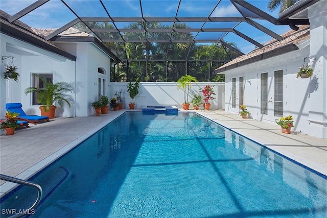 view of swimming pool featuring a lanai, a pool with connected hot tub, a patio, and french doors