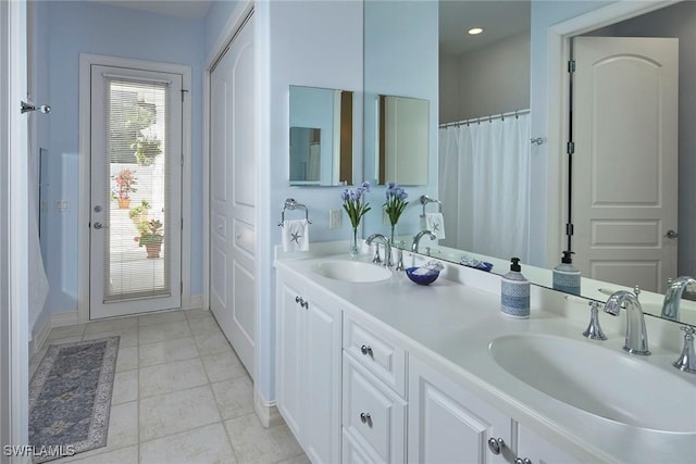 bathroom featuring baseboards, a sink, tile patterned floors, and double vanity