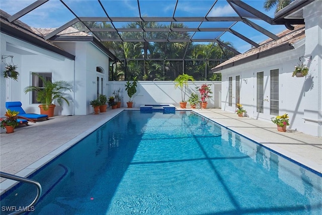 view of swimming pool featuring french doors, glass enclosure, a pool with connected hot tub, and a patio area