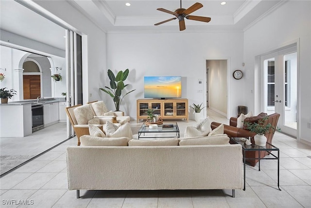 living room featuring ceiling fan, crown molding, light tile patterned floors, a raised ceiling, and wine cooler