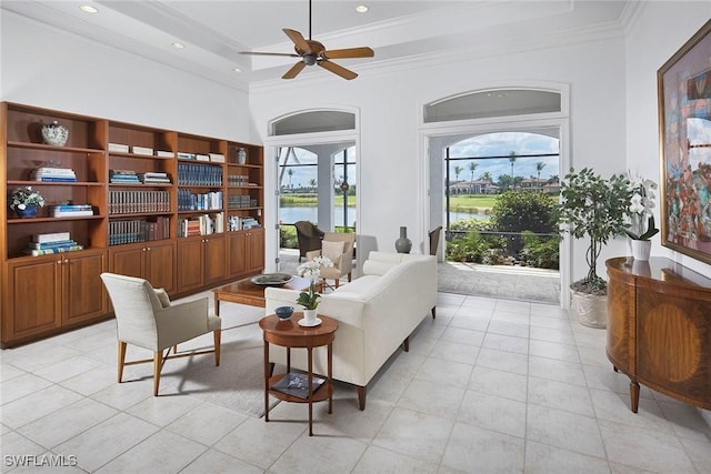 living area featuring light tile patterned floors, a water view, crown molding, and a ceiling fan