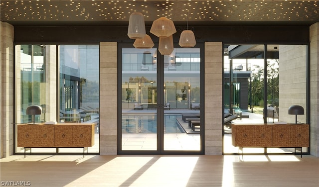 doorway with expansive windows, a wealth of natural light, and light wood-type flooring