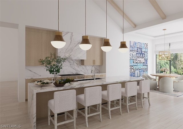 kitchen with light brown cabinetry, light wood-type flooring, light stone countertops, pendant lighting, and an inviting chandelier