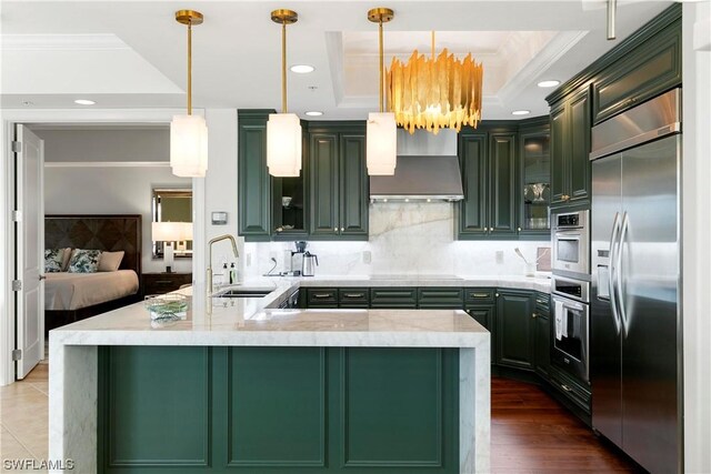 kitchen featuring stainless steel appliances, a tray ceiling, crown molding, sink, and wall chimney range hood