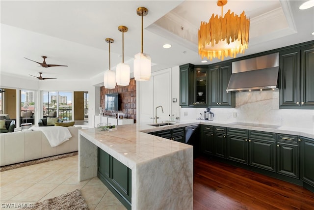 kitchen featuring black electric stovetop, a raised ceiling, ceiling fan, sink, and wall chimney range hood