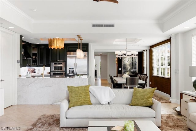 living room with a chandelier, light tile patterned flooring, visible vents, ornamental molding, and a tray ceiling