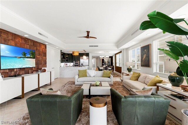 tiled living room with a tray ceiling, crown molding, and ceiling fan with notable chandelier