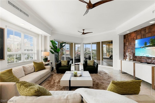 tiled living room featuring a healthy amount of sunlight, ceiling fan, visible vents, and ornamental molding