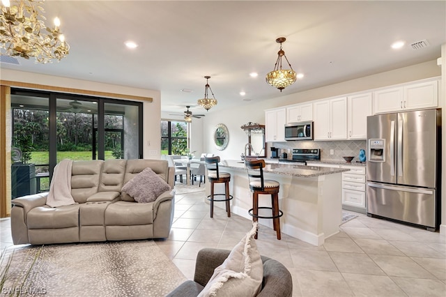 living room featuring ceiling fan with notable chandelier and light tile floors