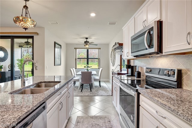 kitchen featuring white cabinetry, hanging light fixtures, appliances with stainless steel finishes, sink, and tasteful backsplash