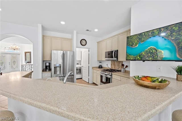 kitchen featuring kitchen peninsula, cream cabinets, stainless steel appliances, and a breakfast bar area