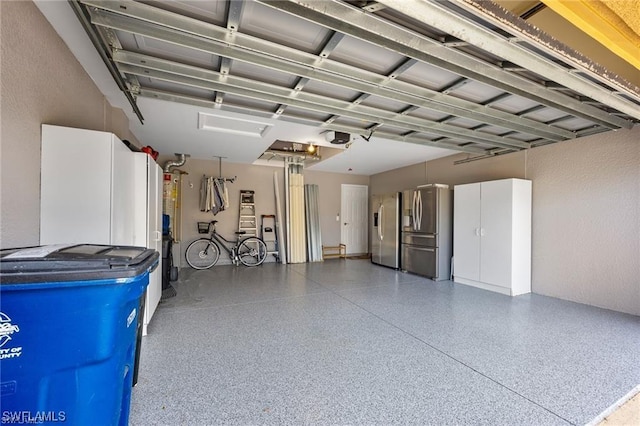 garage with a garage door opener and stainless steel refrigerator with ice dispenser