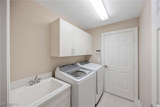 clothes washing area with sink, cabinets, a textured ceiling, light tile patterned floors, and independent washer and dryer