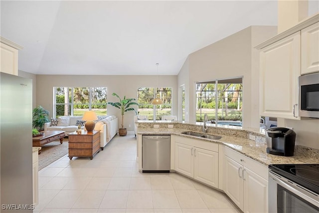 kitchen featuring sink, light stone counters, vaulted ceiling, light tile patterned floors, and stainless steel appliances