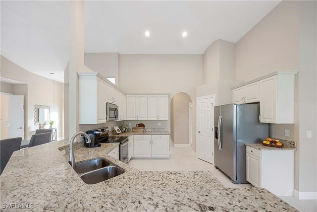 kitchen featuring stainless steel appliances, white cabinetry, light stone countertops, and sink