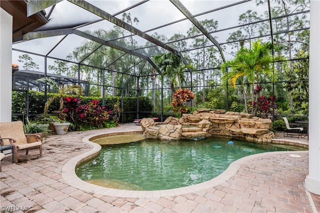 view of pool with pool water feature, glass enclosure, and a patio area