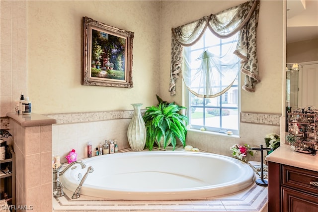 bathroom featuring vanity, tiled bath, and a healthy amount of sunlight