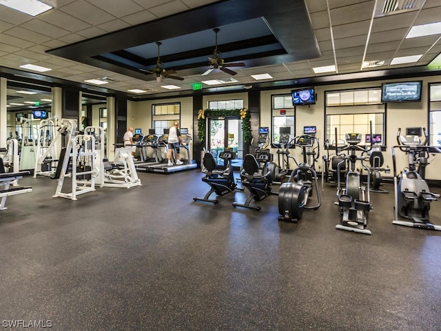 exercise room with a raised ceiling, ceiling fan, and a drop ceiling