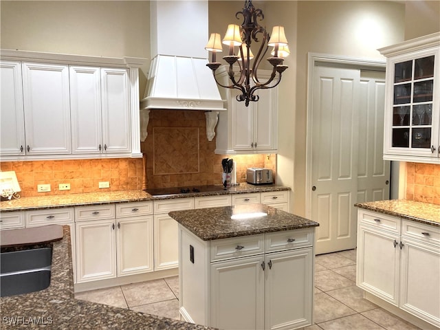 kitchen featuring a center island, tasteful backsplash, premium range hood, a chandelier, and light tile patterned floors