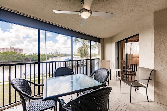 sunroom featuring a water view and a ceiling fan